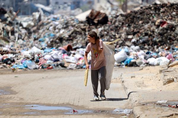A Palestinian child transporting pieces of wood walks past a rubbish dump in Gaza City on Friday, amid the o<em></em>ngoing co<em></em>nflict between Israel and the militant group Hamas. (AFP)